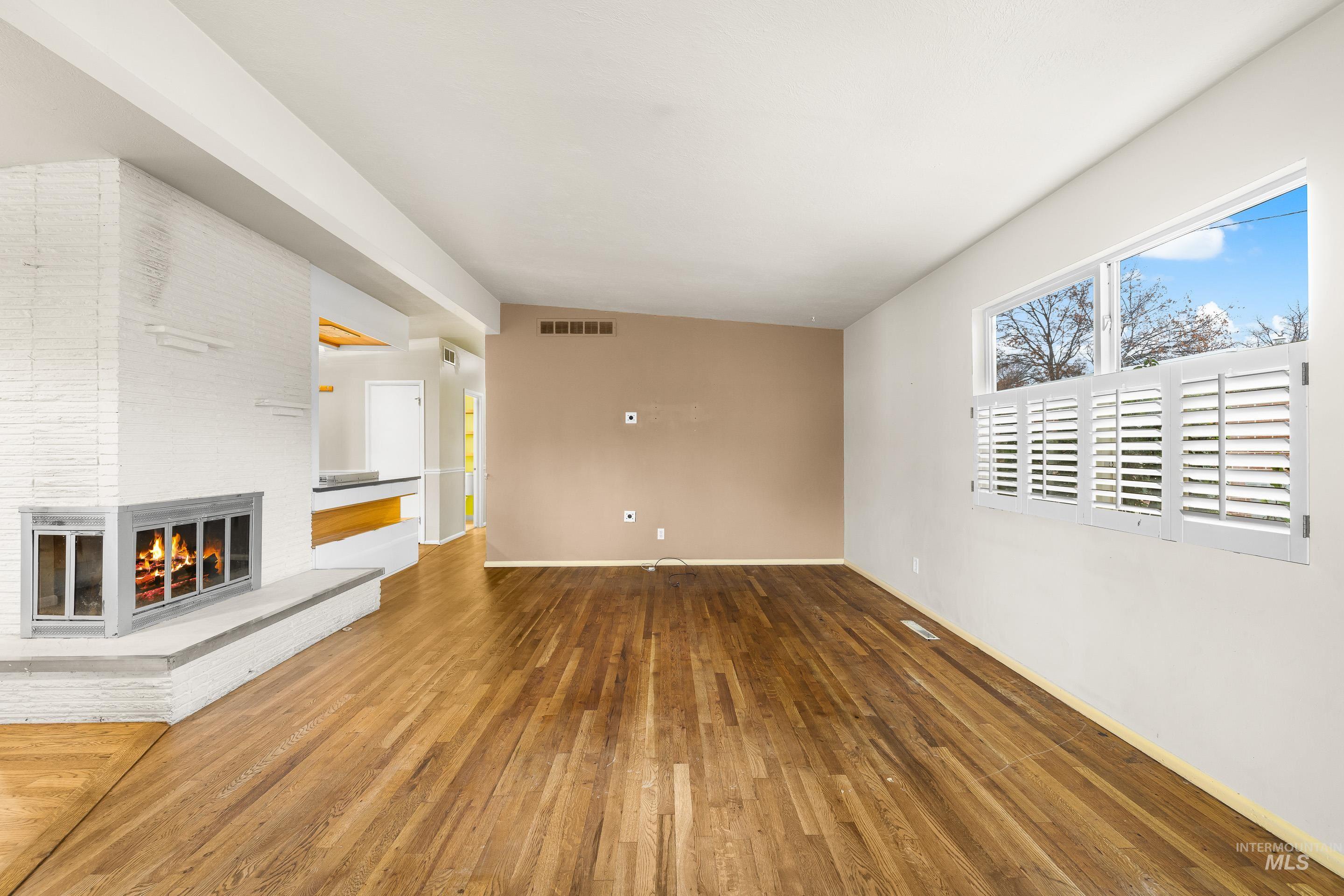 Unfurnished living room featuring a brick fireplace and hardwood / wood-style flooring