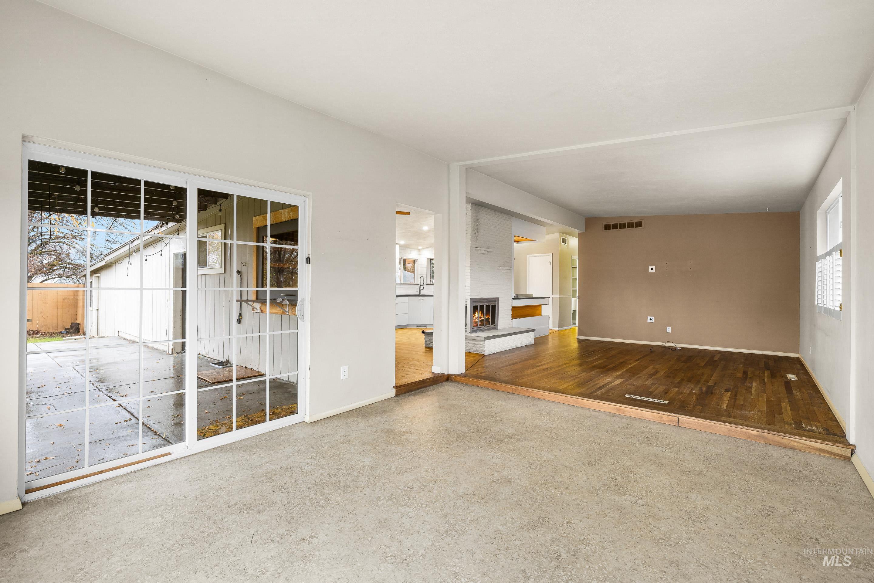 Unfurnished living room featuring a warm lit fireplace and baseboards