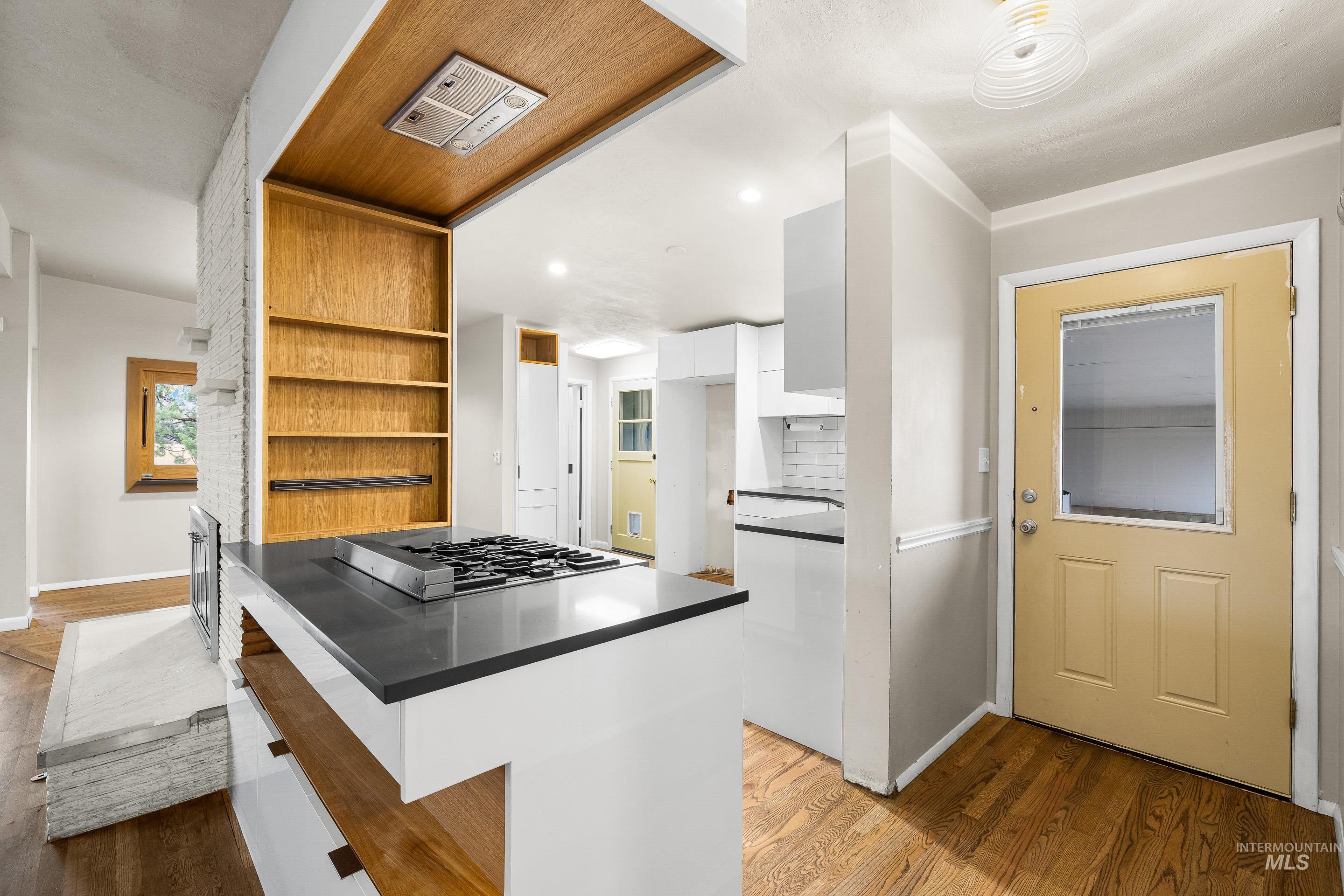 Kitchen featuring dark countertops, white cabinets, light wood-style flooring, open shelves, and stainless steel gas cooktop