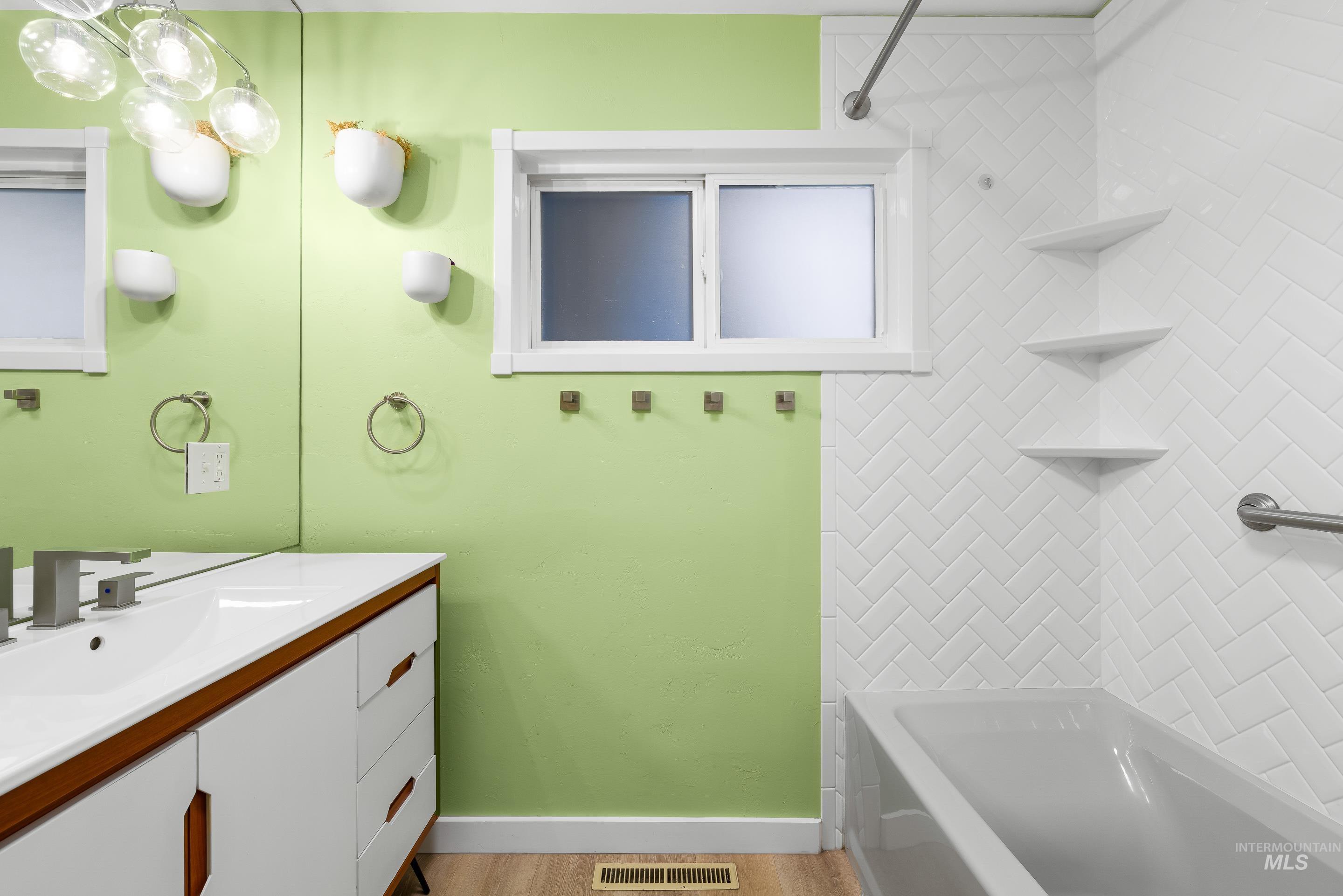 Bathroom featuring vanity, shower / washtub combination, and light wood-type flooring
