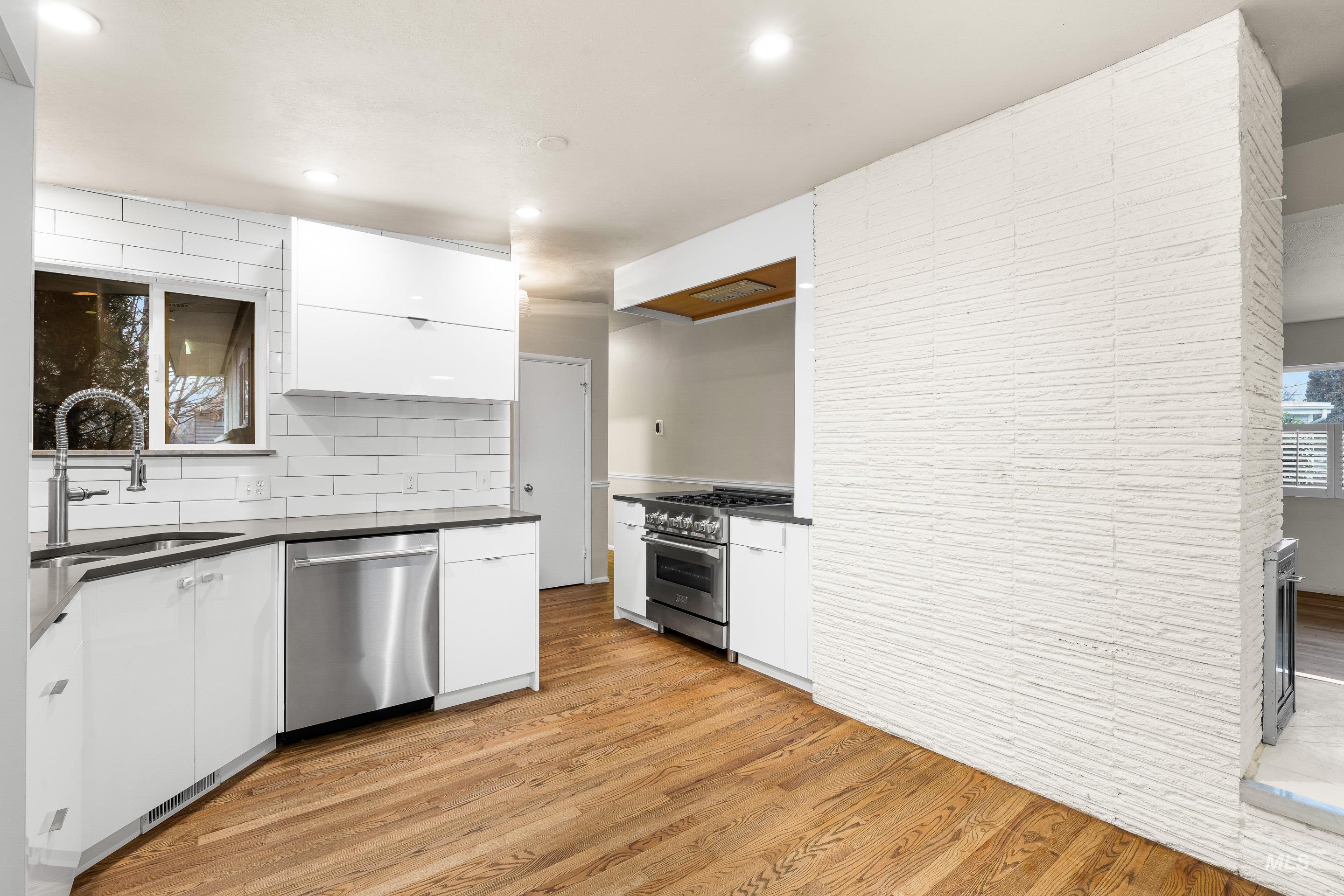 Kitchen featuring white cabinets, stainless steel appliances, light wood-style flooring, modern cabinets, and recessed lighting