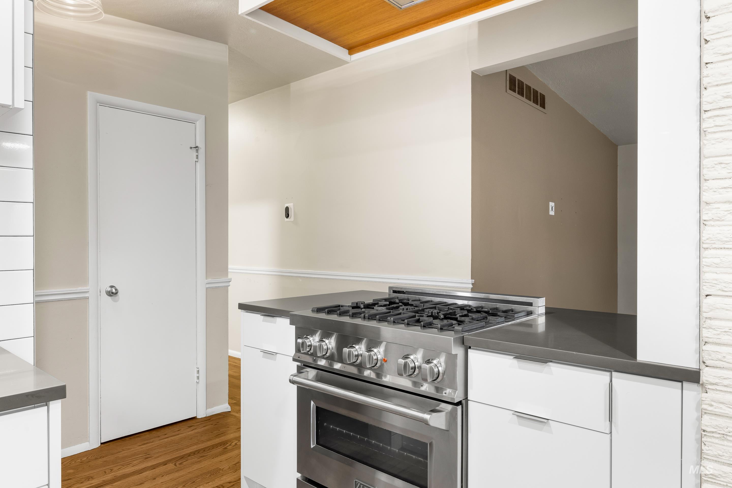 Kitchen with white cabinets, high end stove, and modern cabinets