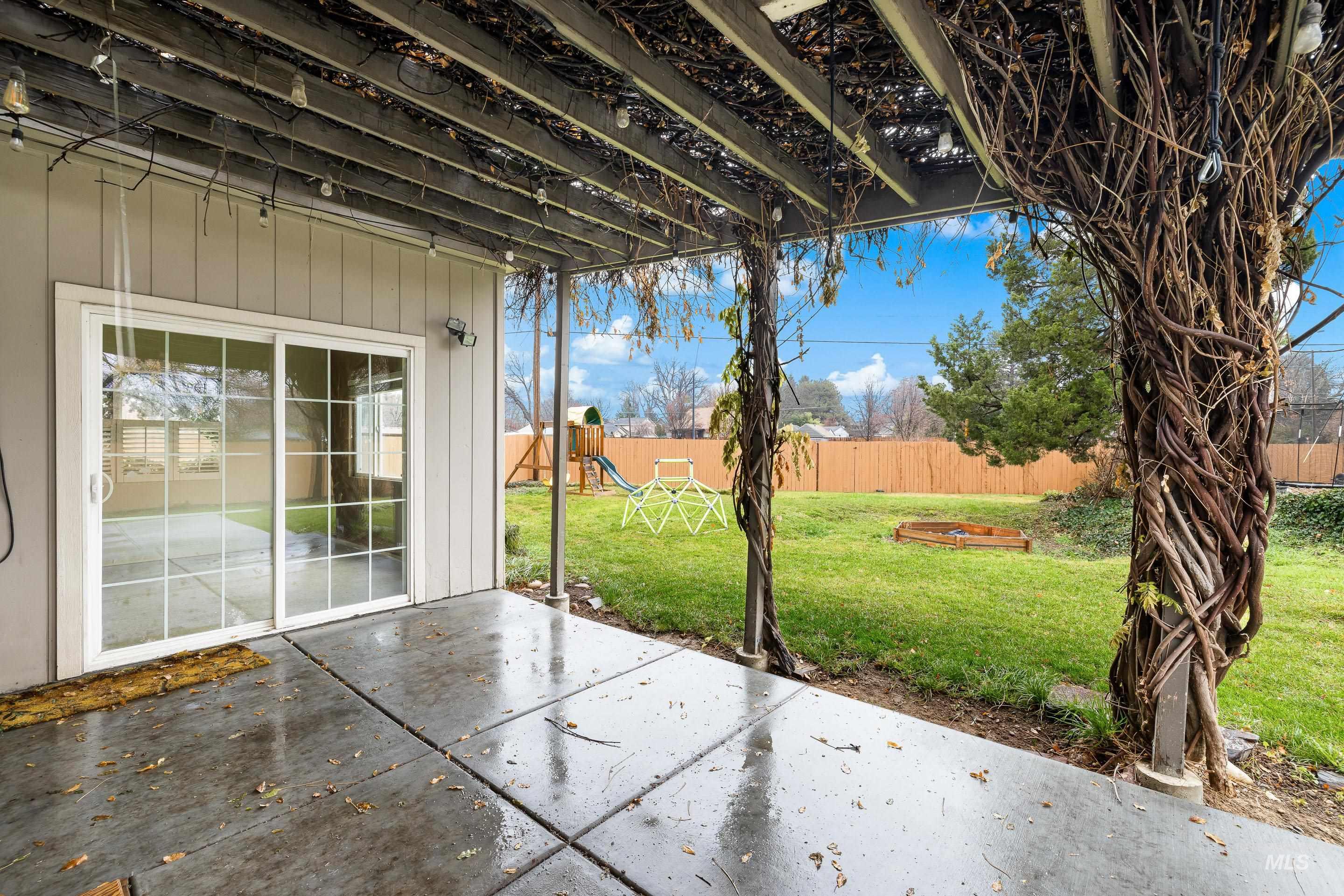 Fenced backyard with a patio and a playground