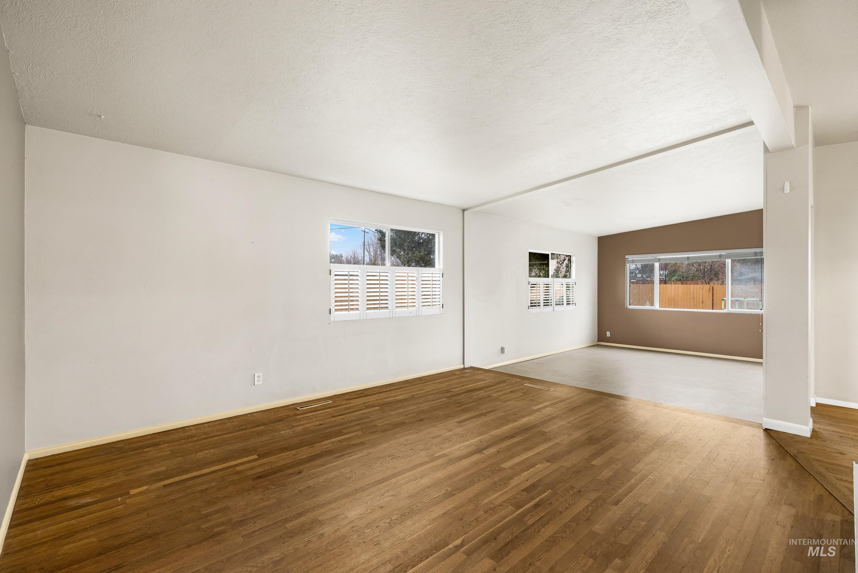 Spare room featuring wood finished floors, healthy amount of natural light, and a textured ceiling