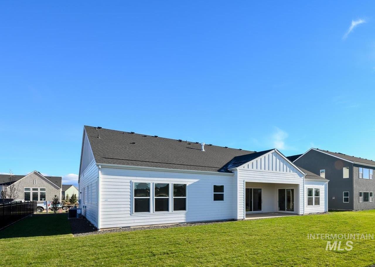 Expansive backyard featuring a manicured lawn, low-maintenance rock landscaping, and young evergreen plantings