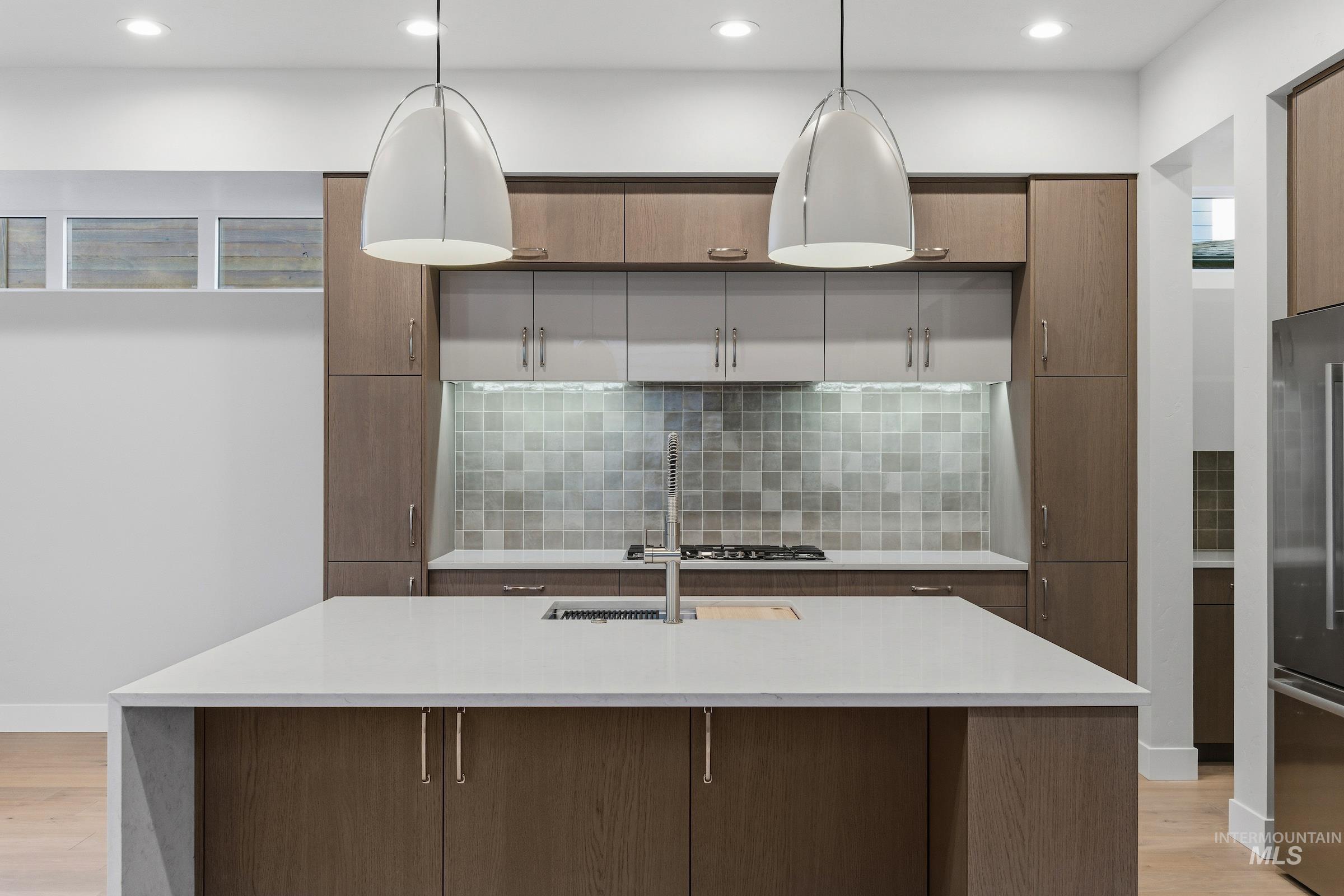 Kitchen featuring light wood finished floors, light stone countertops, hanging light fixtures, and recessed lighting