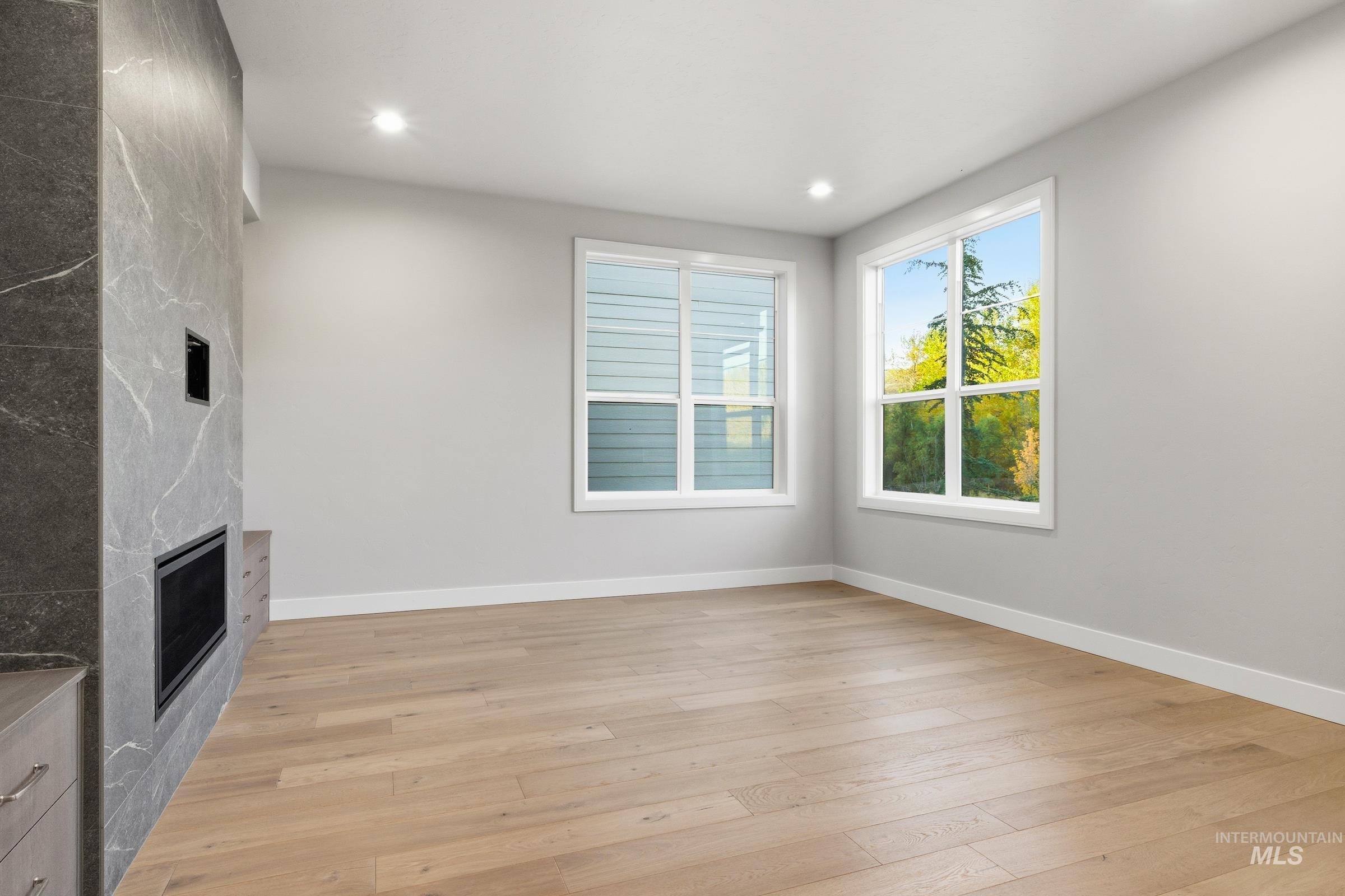 Unfurnished living room featuring a fireplace, light wood-style flooring, and recessed lighting