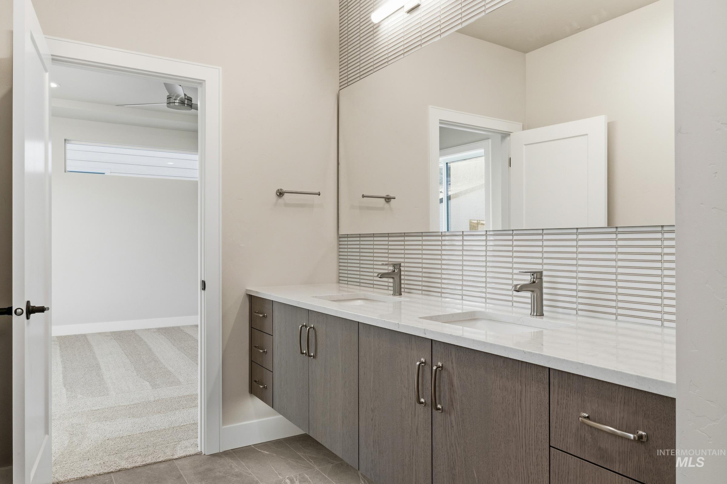 Bathroom with double vanity, tasteful backsplash, light tile patterned flooring, and light carpet