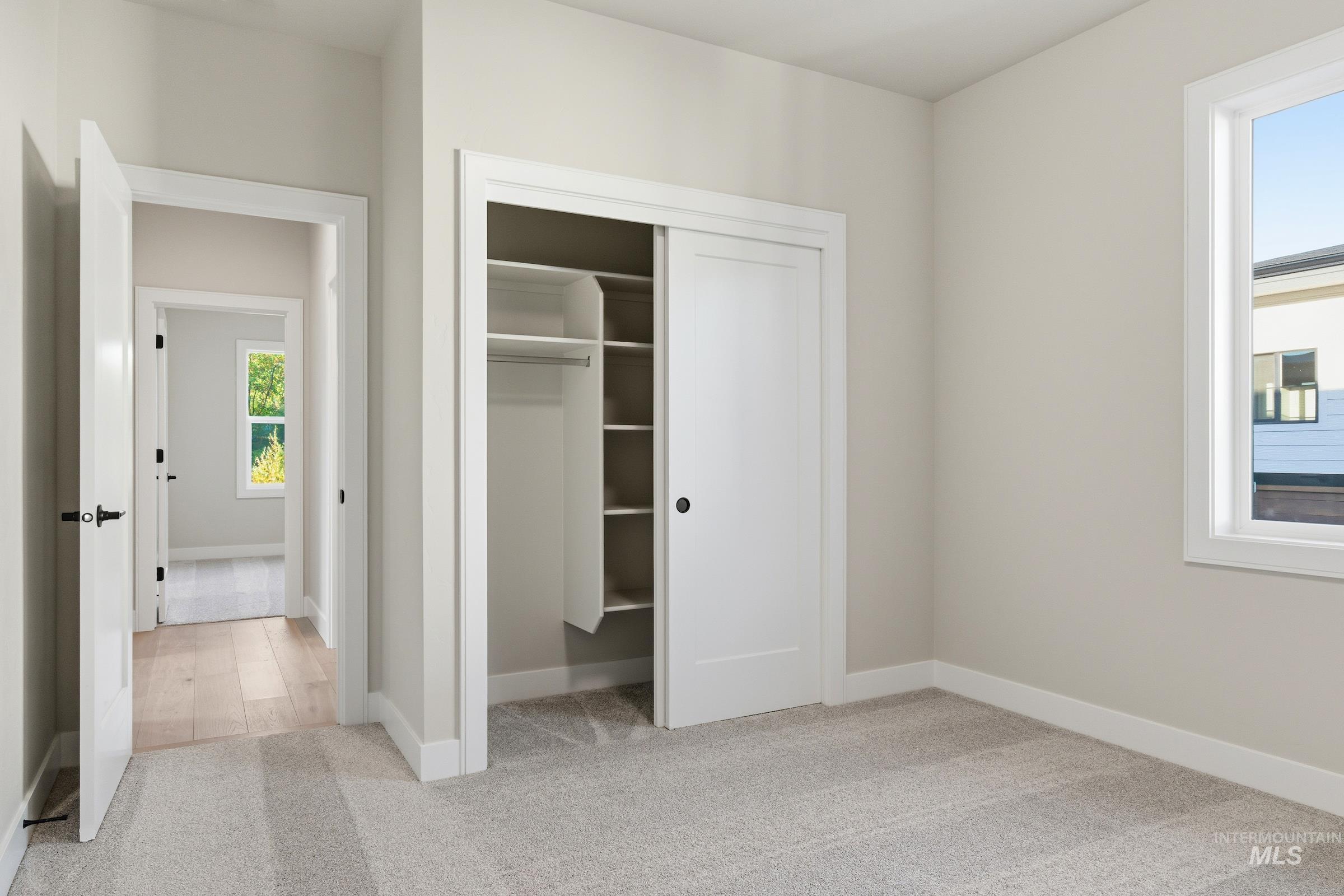 Unfurnished bedroom with light colored carpet, multiple windows, and a closet