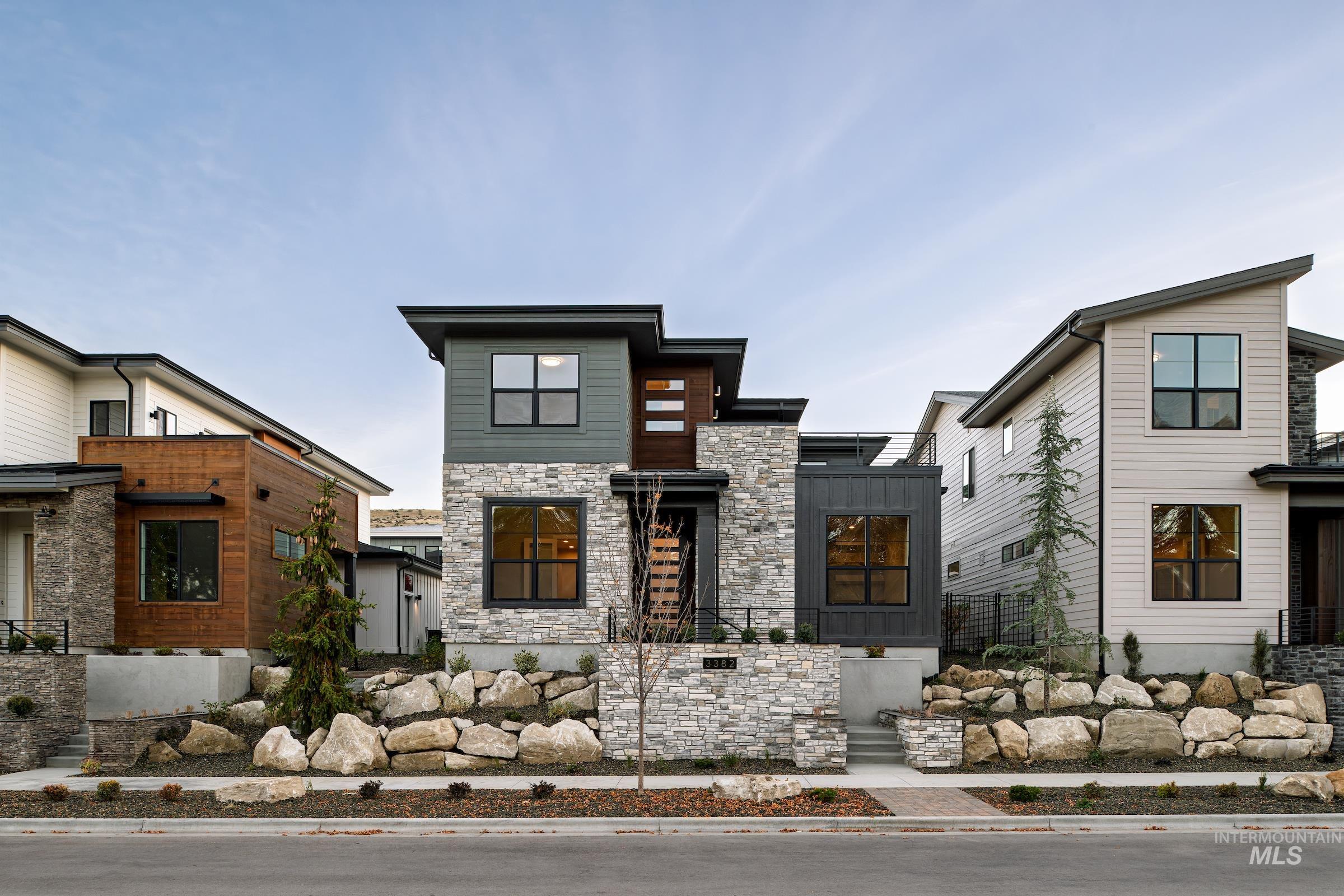 Contemporary home featuring stone siding, a fenced front yard, and board and batten siding