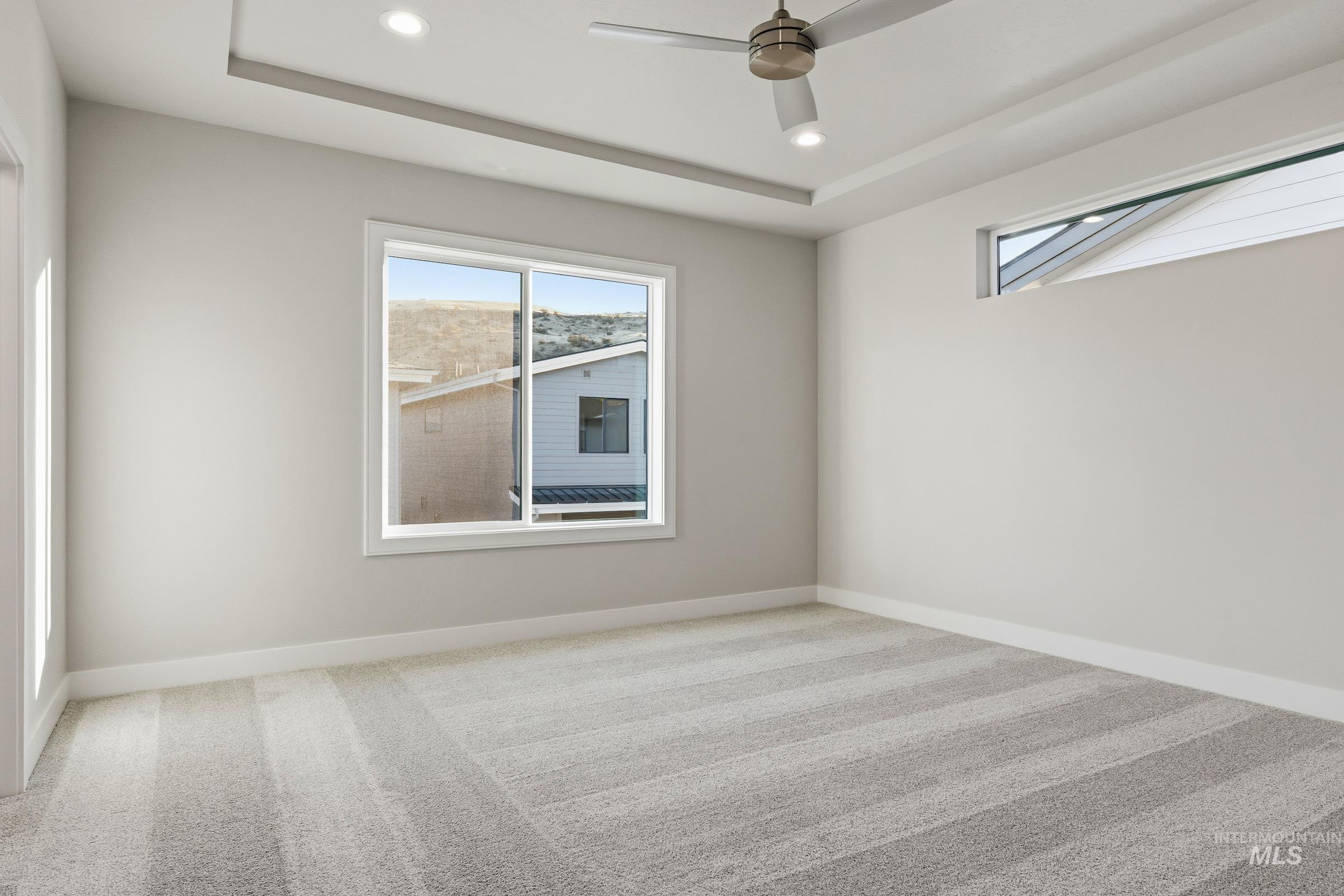 Unfurnished room featuring carpet flooring, a raised ceiling, recessed lighting, and a ceiling fan