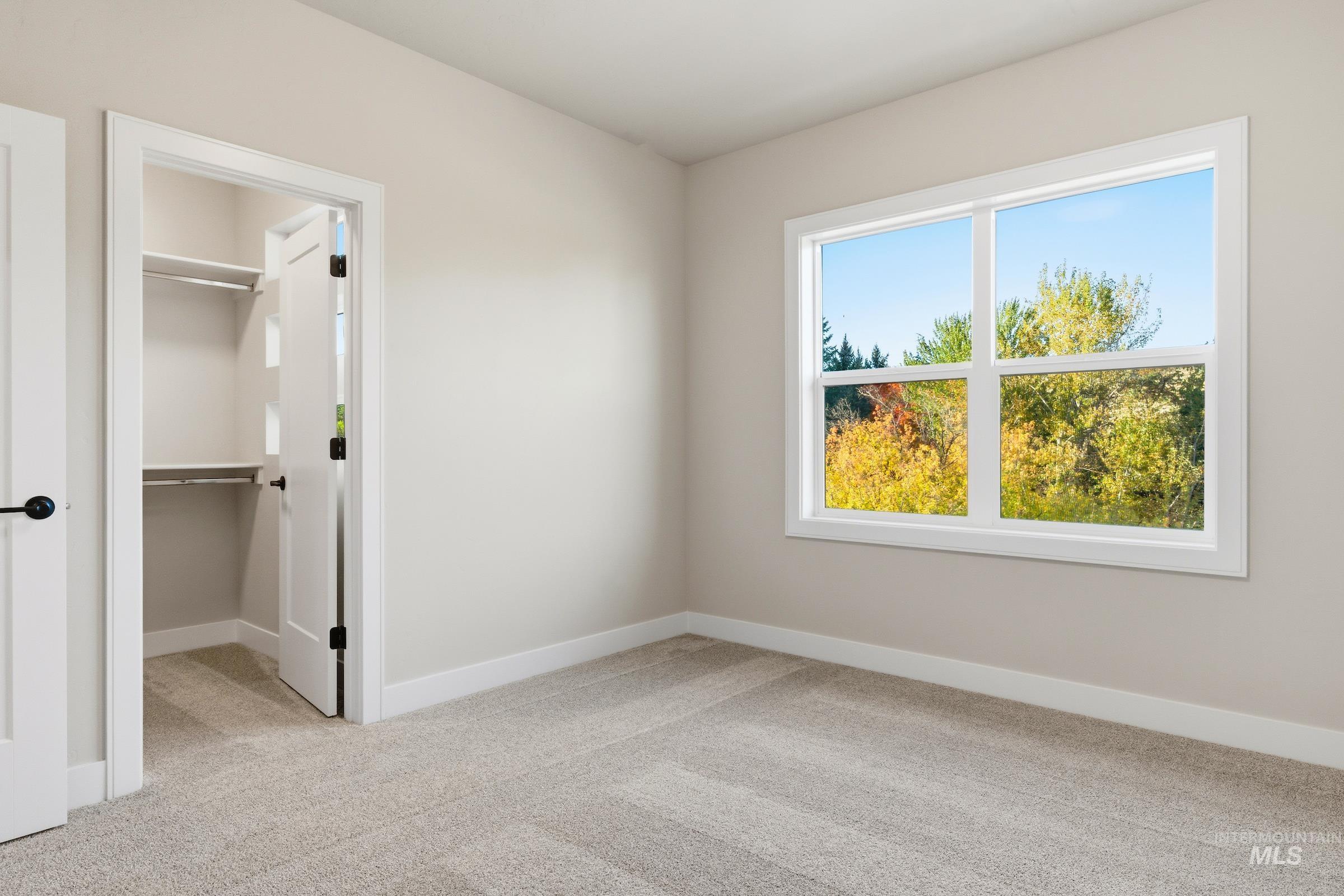 Unfurnished bedroom with light carpet and a spacious closet