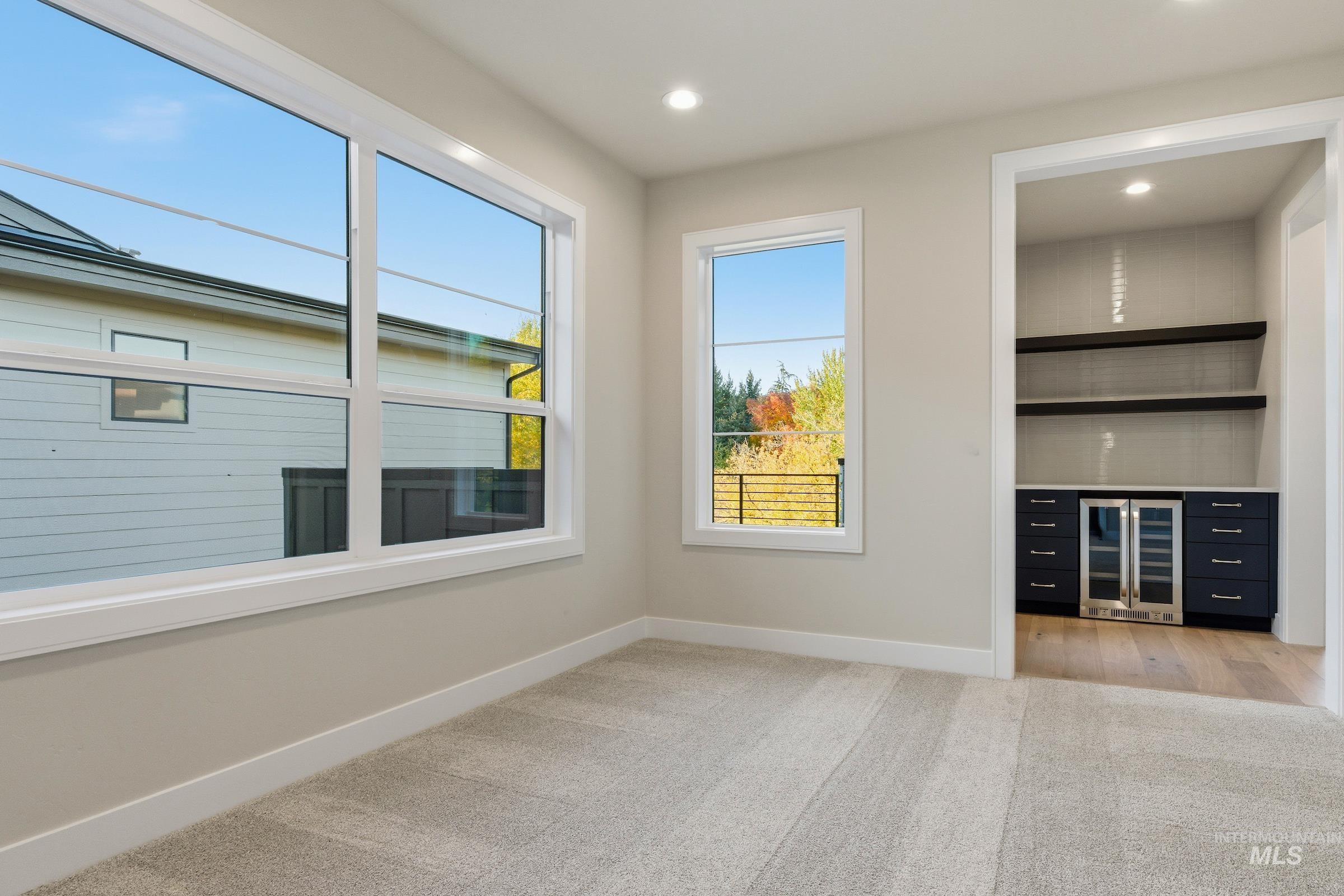 Empty room with light carpet, beverage cooler, and recessed lighting