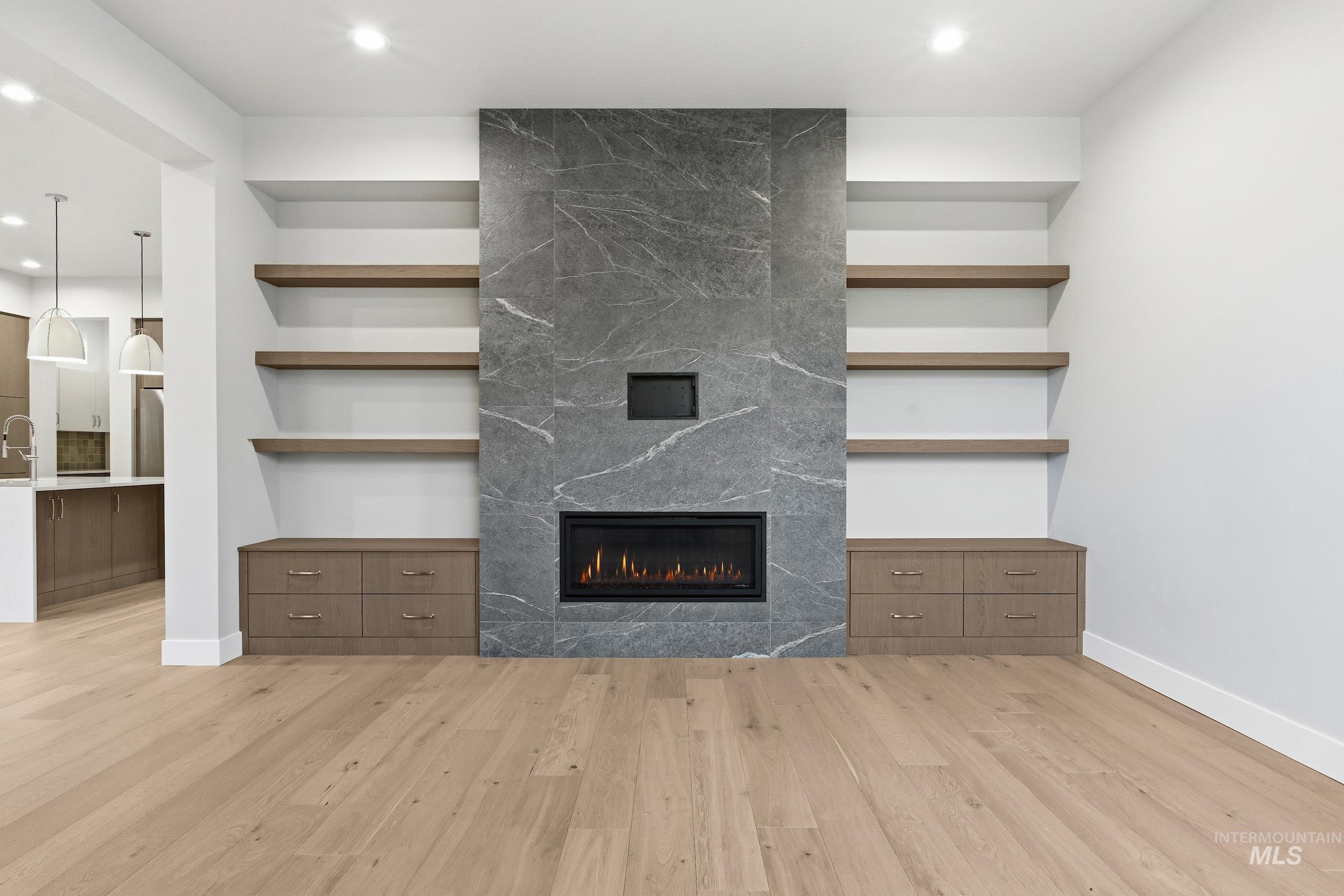 Unfurnished living room featuring built in features, recessed lighting, light wood-style flooring, and a fireplace
