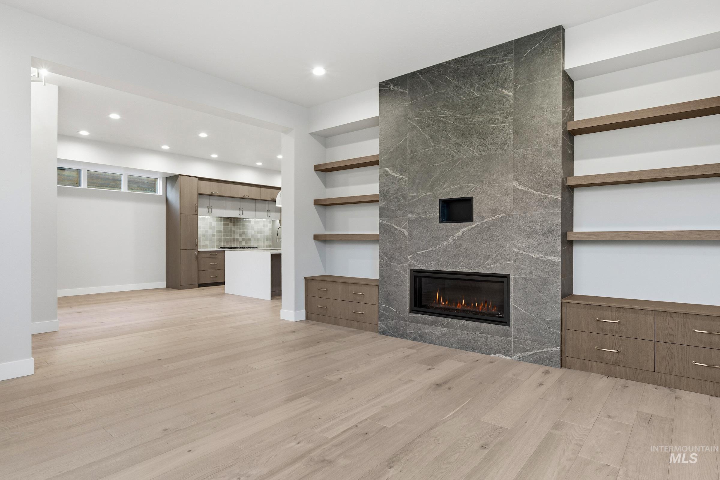 Unfurnished living room featuring light wood finished floors, a fireplace, recessed lighting, and built in shelves