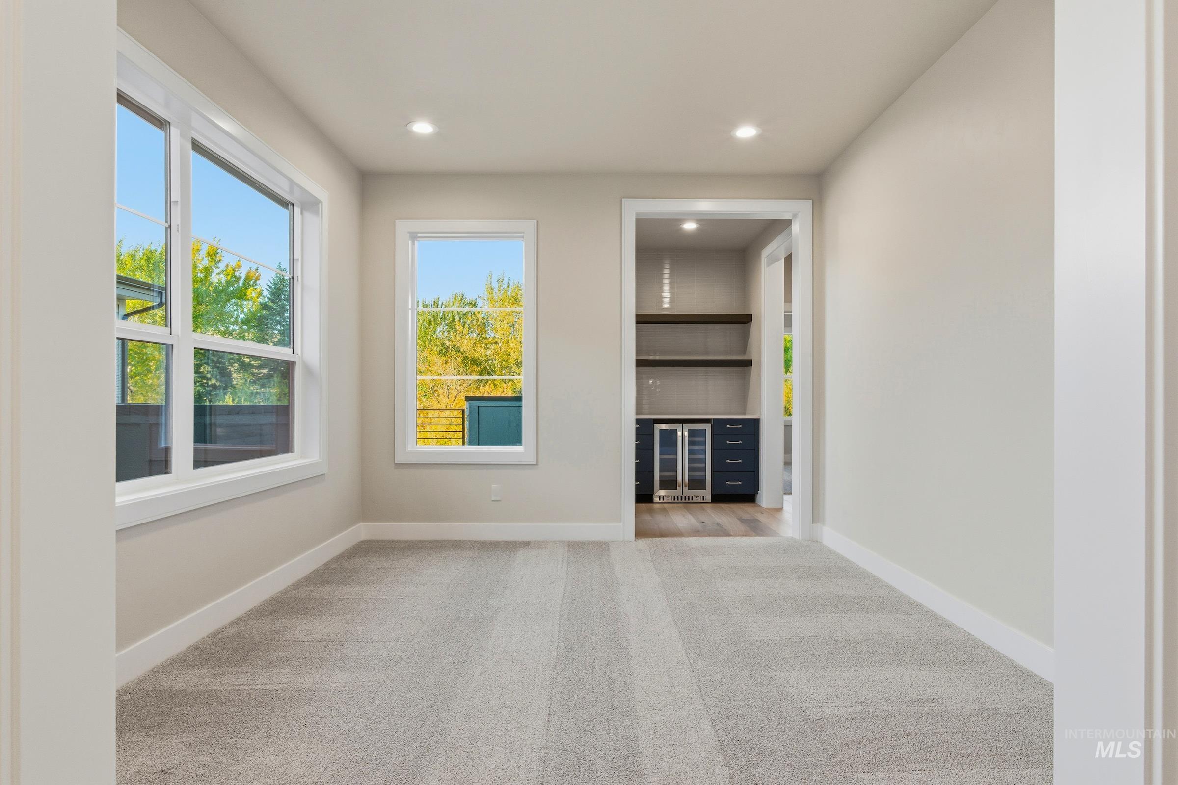 Unfurnished living room with light colored carpet, beverage cooler, and recessed lighting