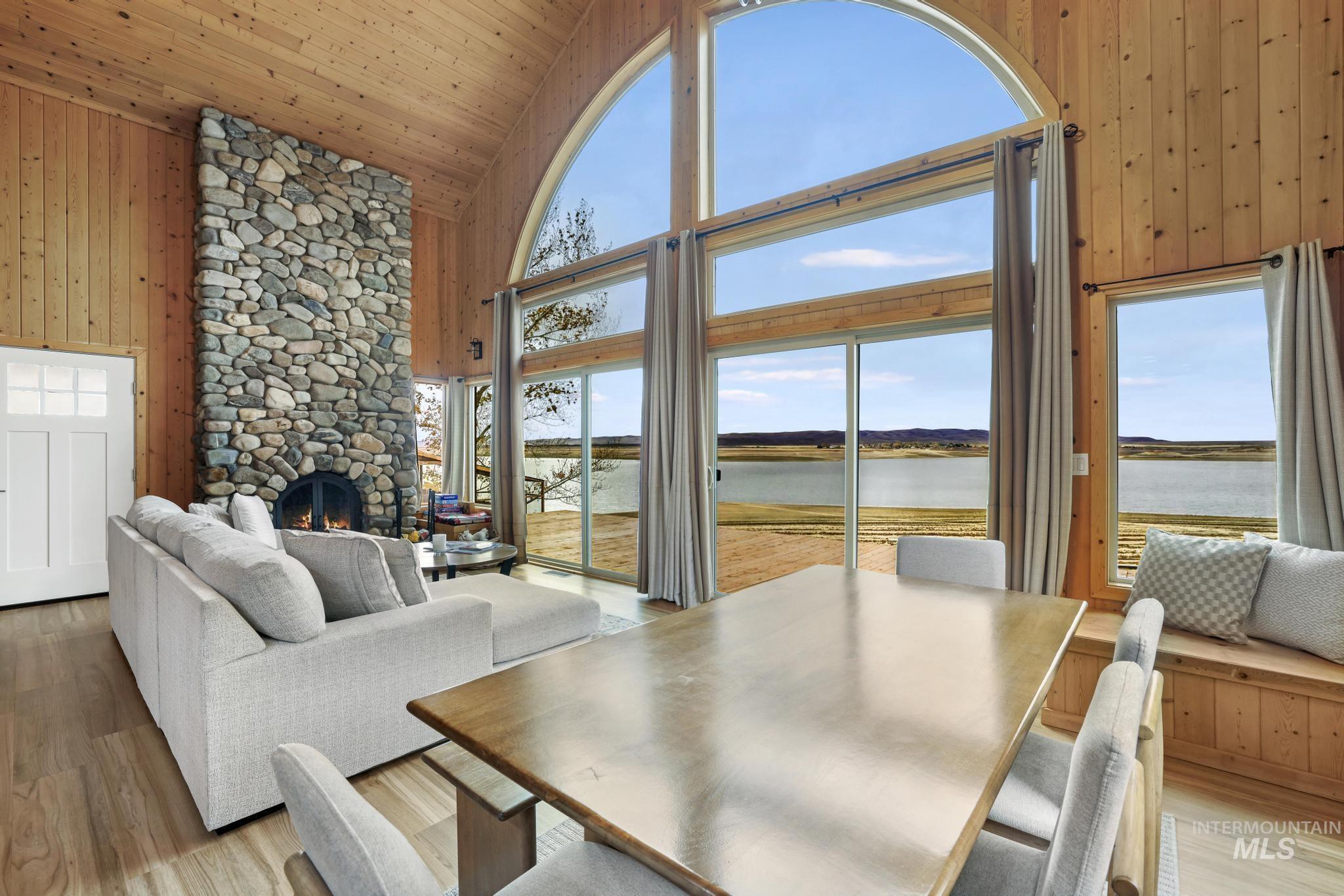 Dining space featuring wood walls, high vaulted ceiling, healthy amount of natural light, a water view, and wood finished floors