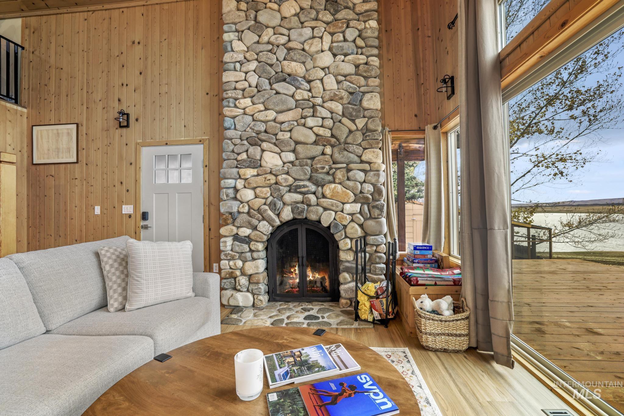 Living room with wood walls, a towering ceiling, healthy amount of natural light, wood finished floors, and a fireplace
