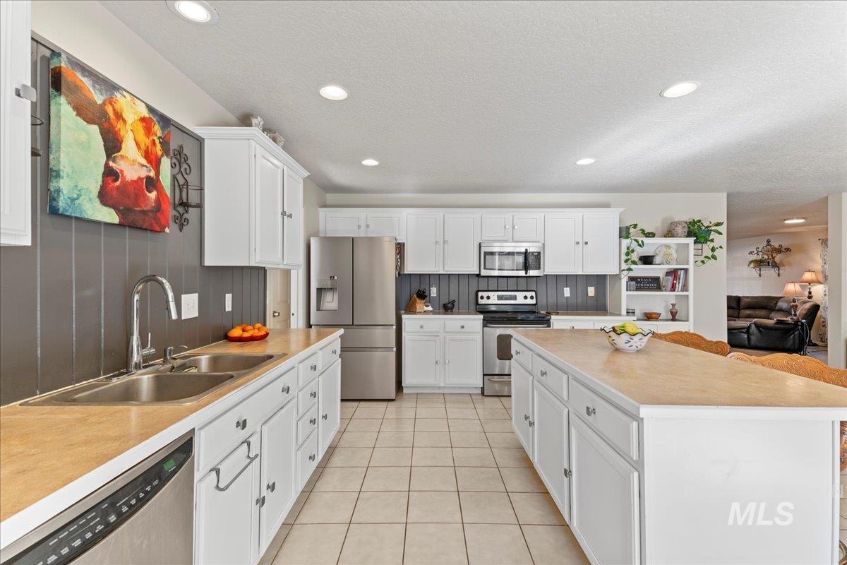 Kitchen featuring appliances with stainless steel finishes, white cabinets, recessed lighting, light tile patterned flooring, and light countertops