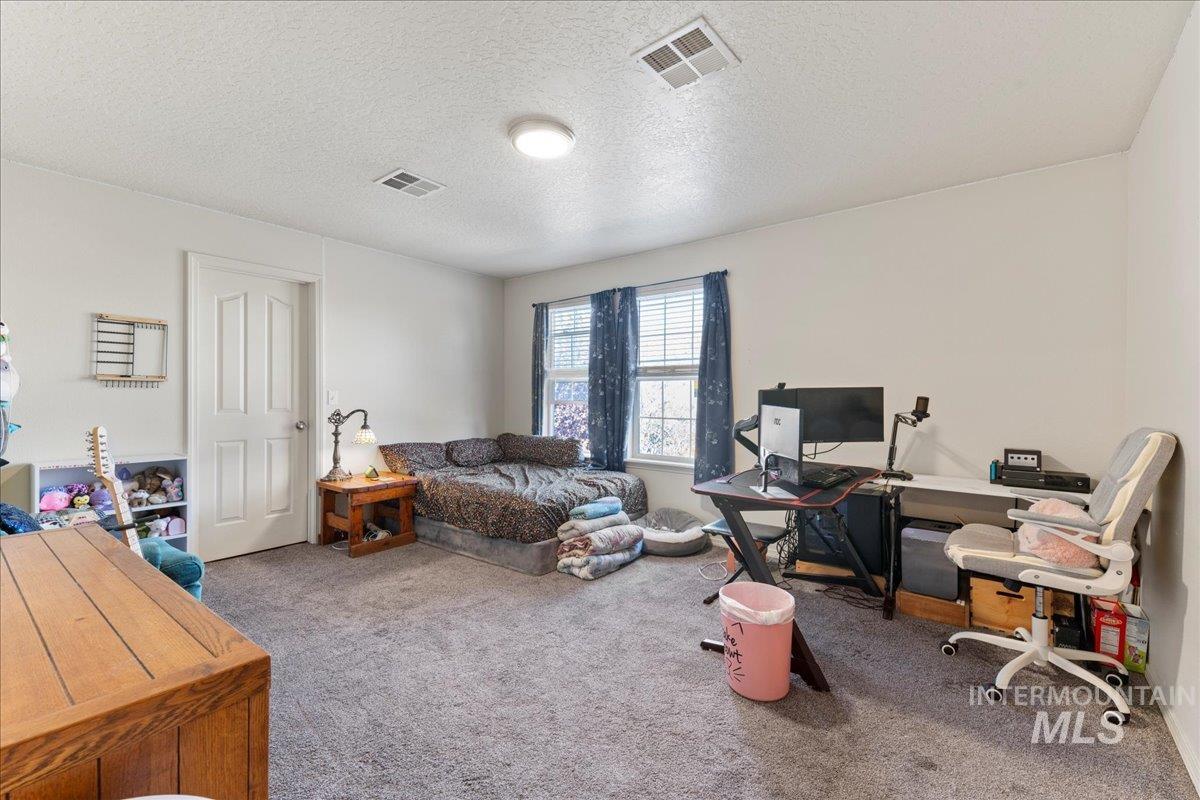 Bedroom with light carpet and a textured ceiling