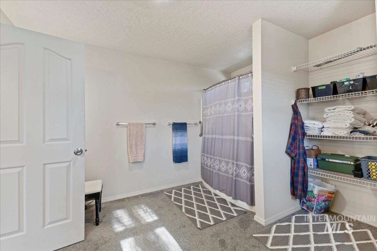Bathroom with a shower with shower curtain, a textured ceiling, and carpet flooring