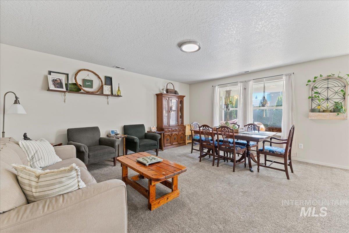 Carpeted living area with a textured ceiling and baseboards