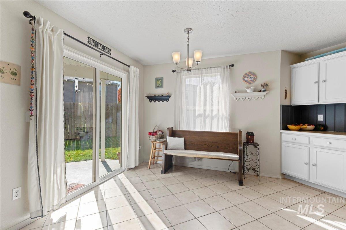 Dining space with light tile patterned floors, a textured ceiling, and a chandelier