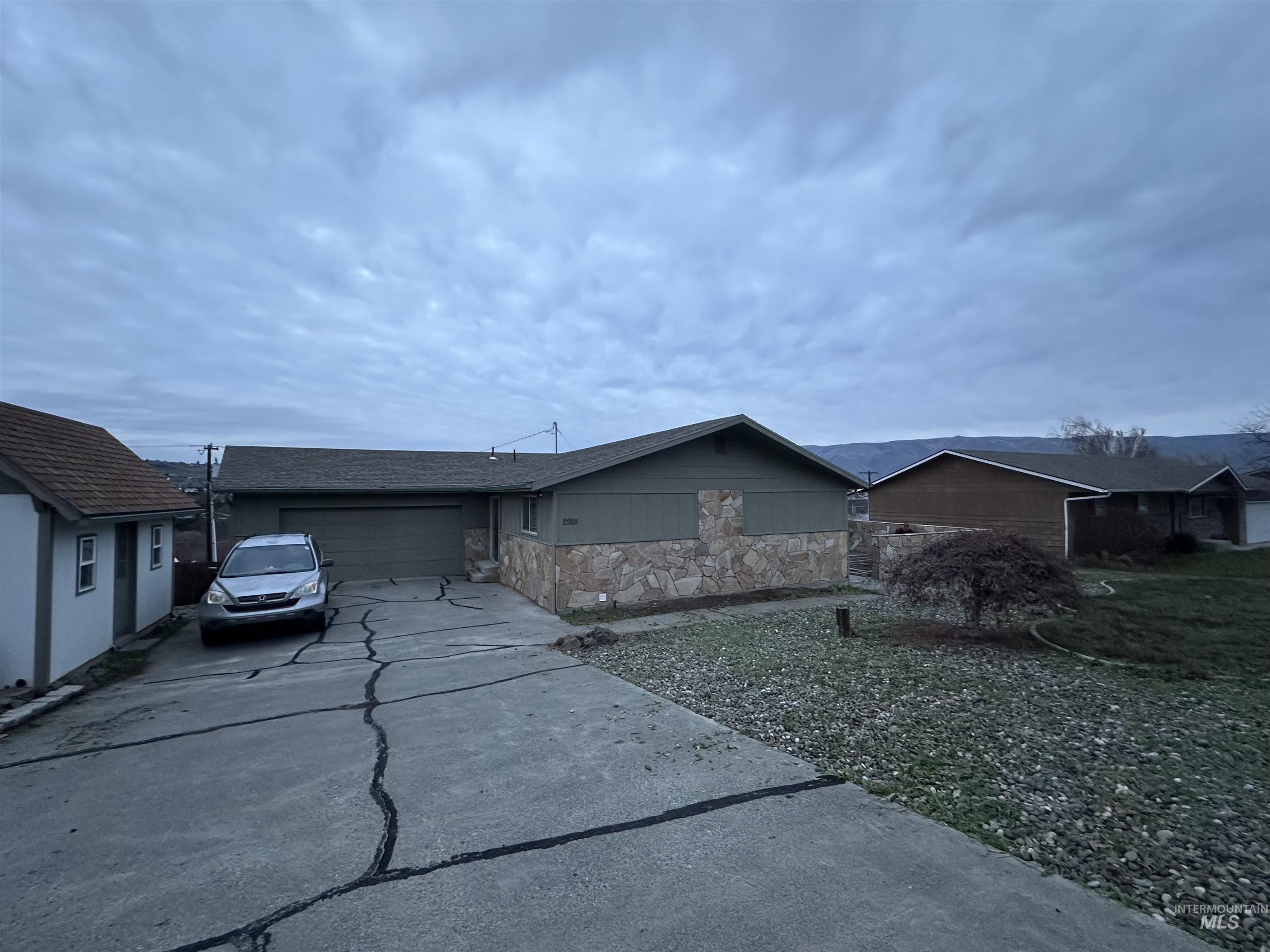 View of front of house with concrete driveway, a garage, and a shingled roof