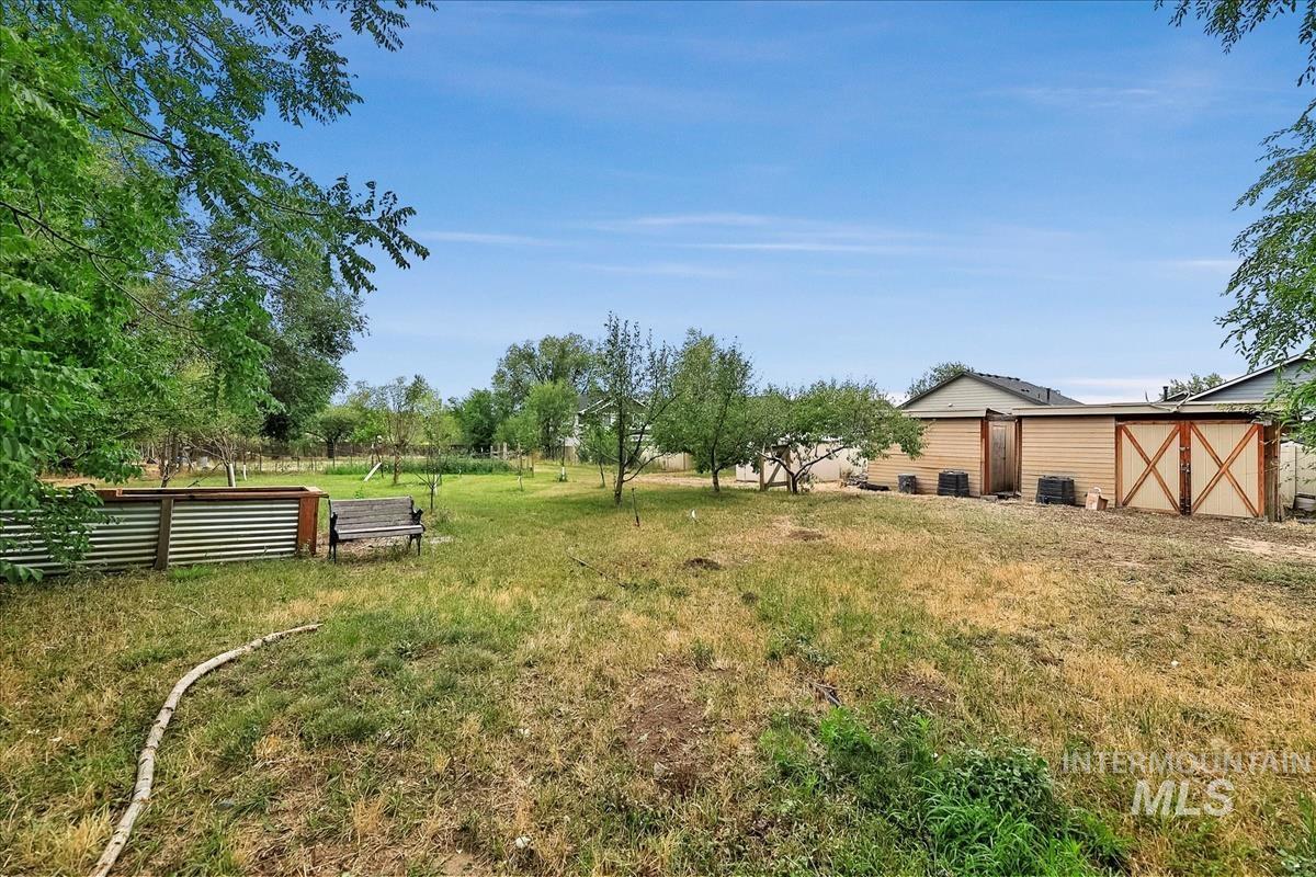 Expansive exterior space featuring mature trees and a substantial outbuilding with wood paneling