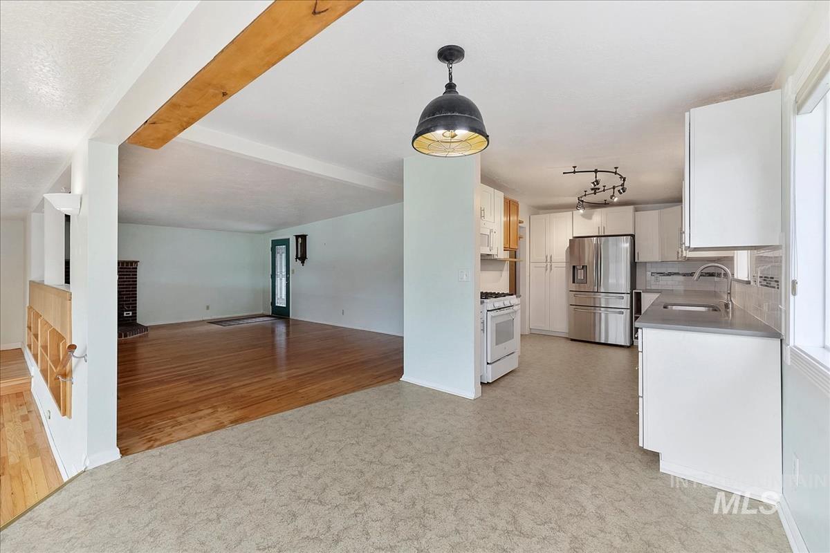 Modern kitchen with light cabinetry, stainless steel refrigerator, white range, gray countertops, and tiled backsplash