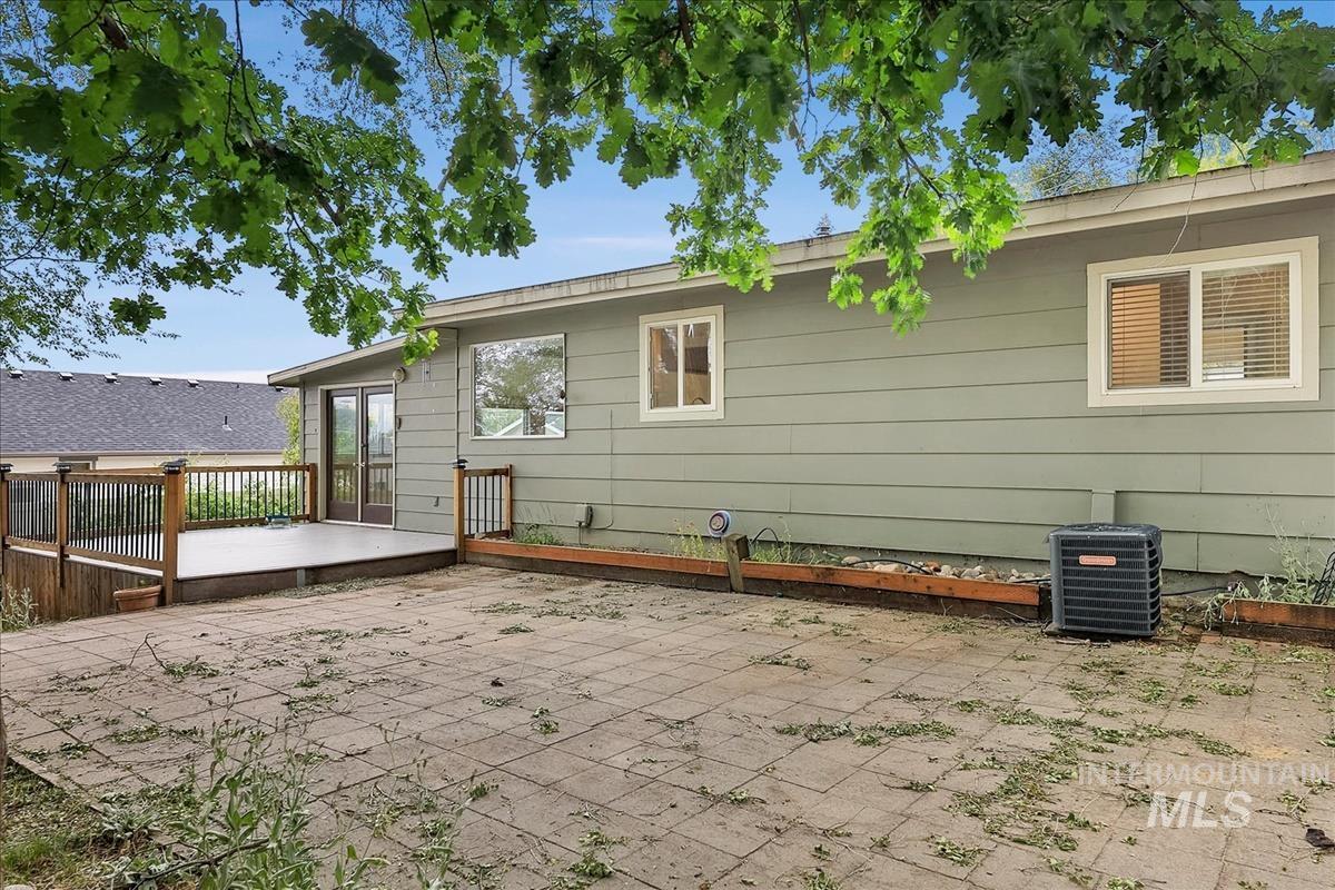 Expansive rear patio featuring square pavers and a raised wood-decked area
