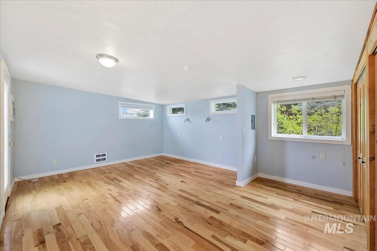 Spacious room featuring light wood-finish flooring, light blue walls, and multiple windows
