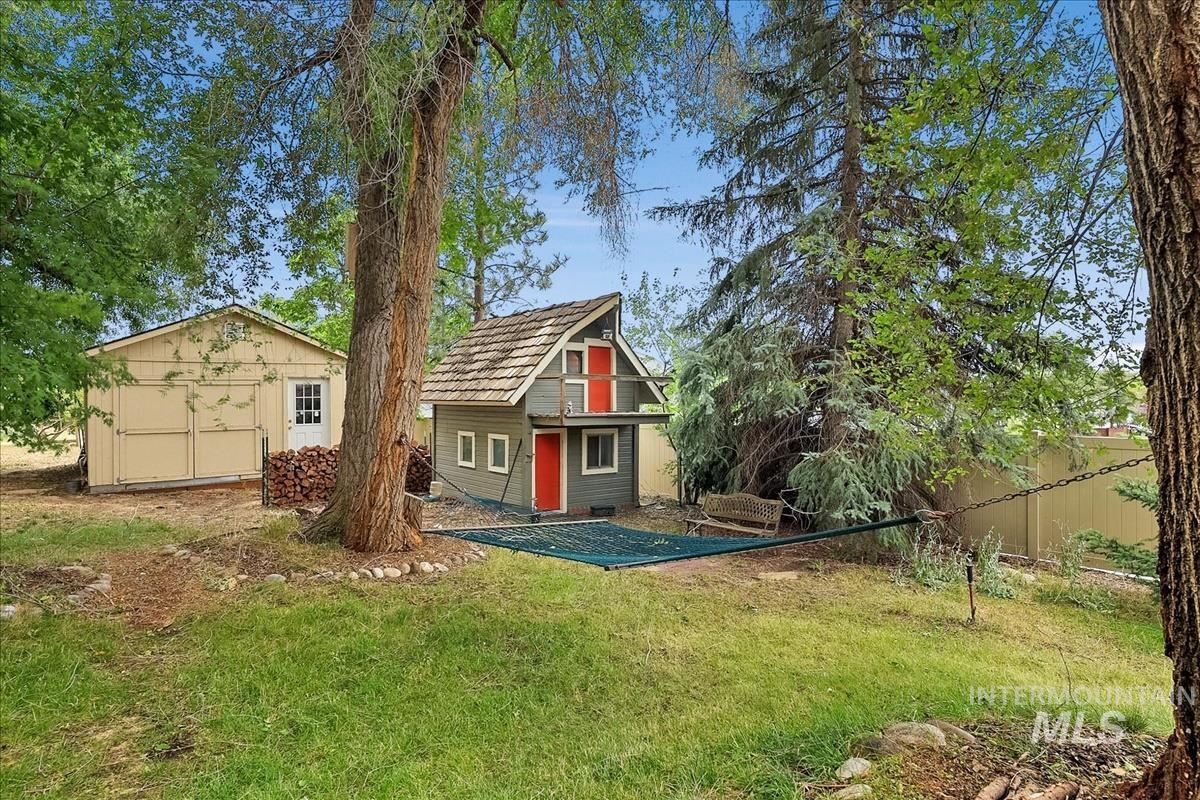 Expansive grassy yard featuring a detached auxiliary building and a smaller secondary structure with a balcony