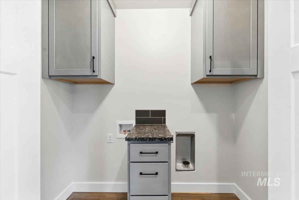 Washroom with washer hookup, cabinet space, and wood finished floors