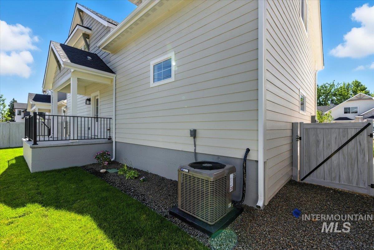 View of side of property featuring a cooling unit and a gate