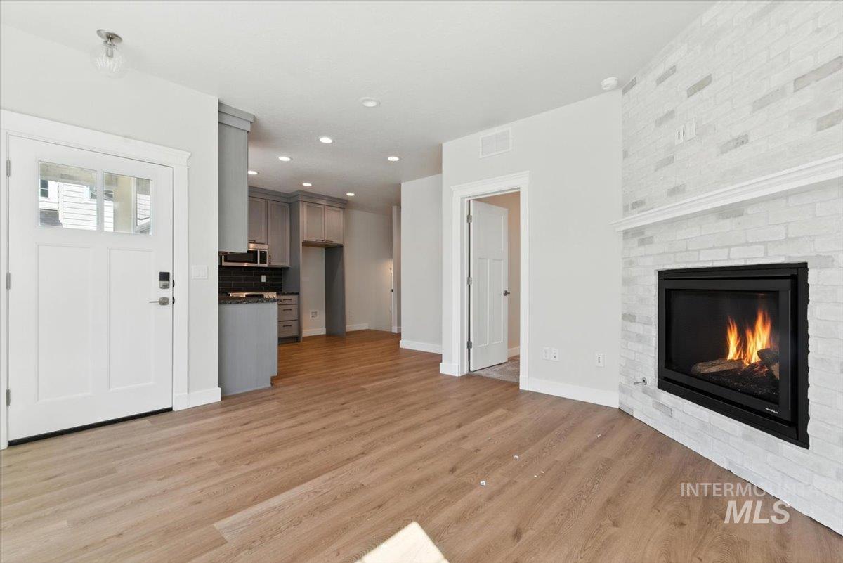 Unfurnished living room featuring light wood-style floors, a brick fireplace, and recessed lighting