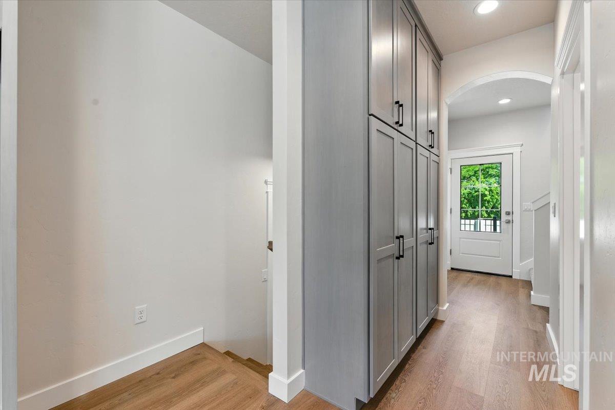 Corridor with arched walkways, light wood-style floors, and recessed lighting