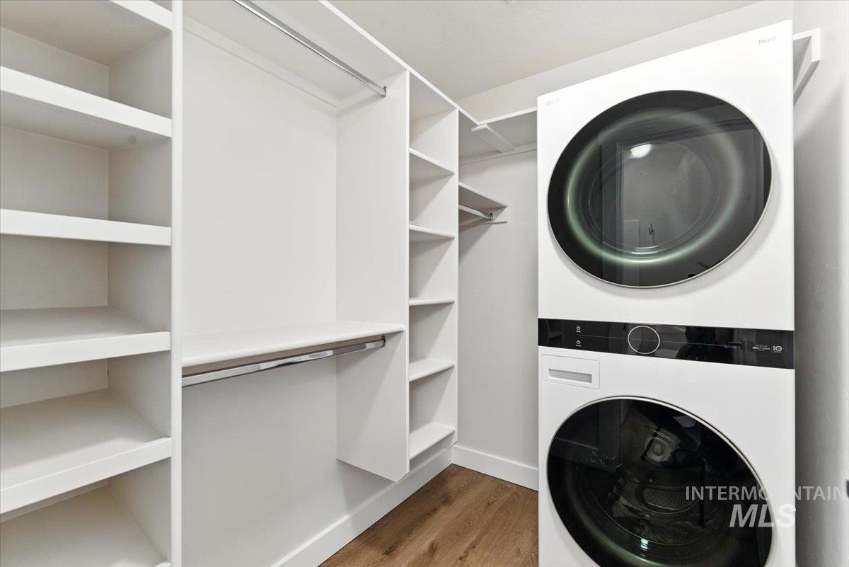 Washroom with estacked washer and dryer and wood finished floors