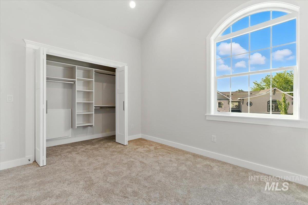 Unfurnished bedroom featuring carpet floors, a closet, and lofted ceiling
