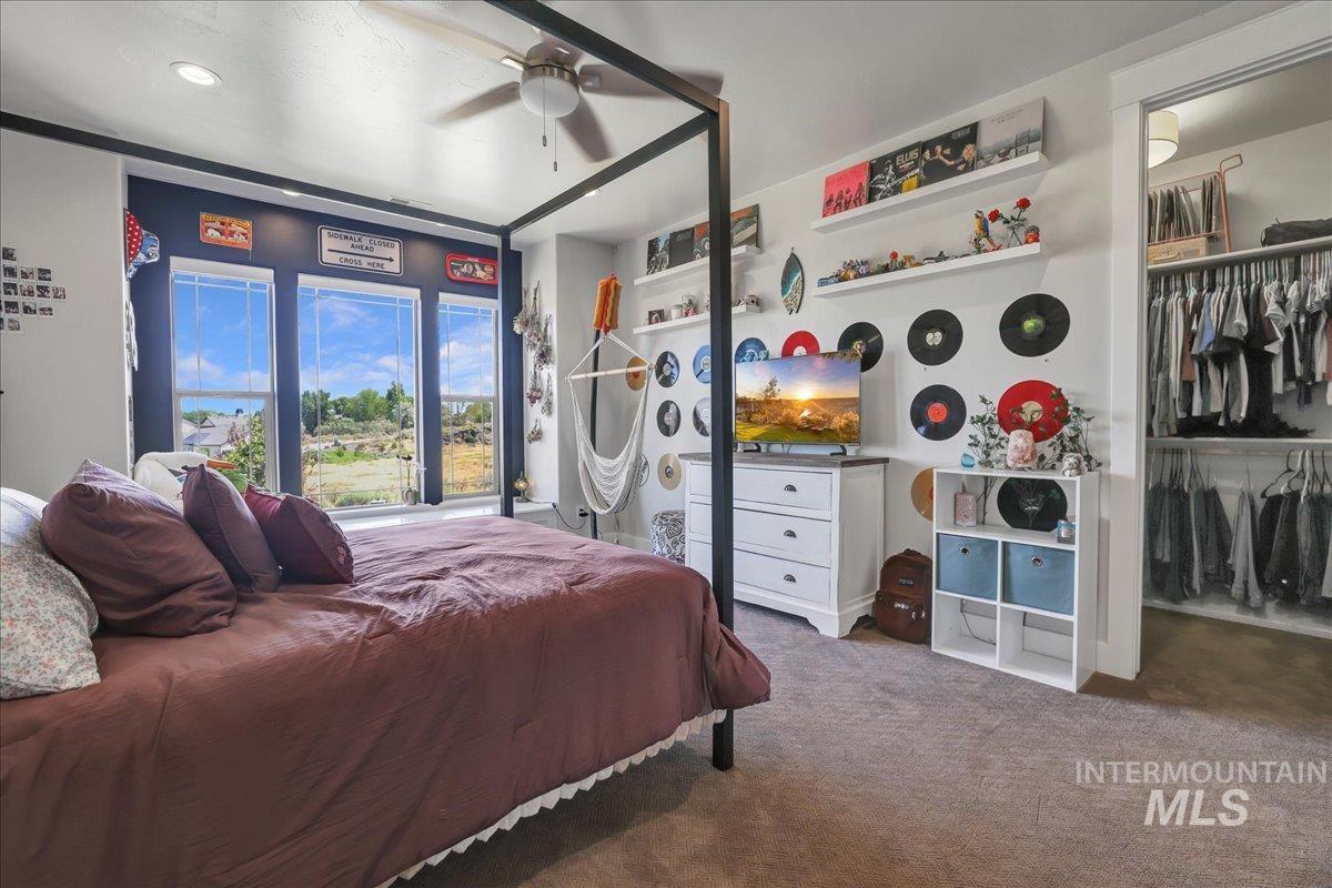 Carpeted bedroom with ceiling fan and a closet