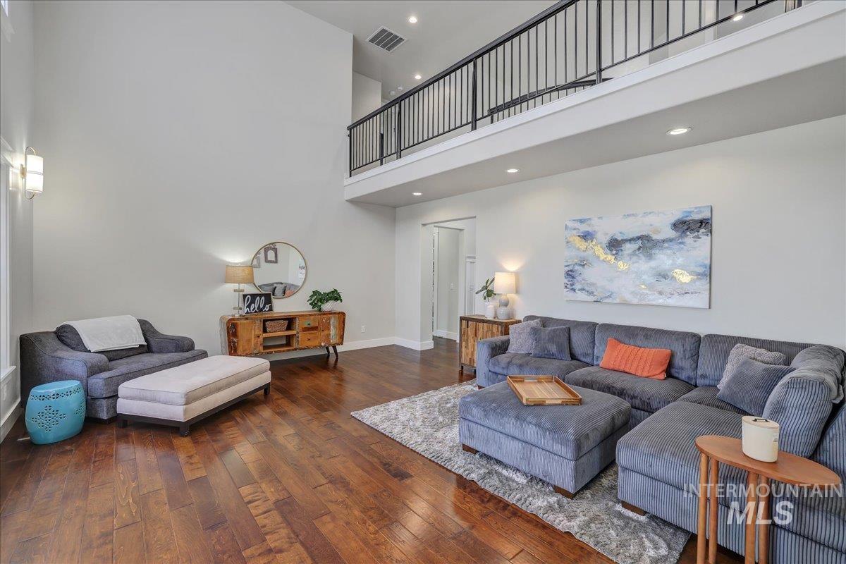 Living area featuring a high ceiling, wood-type flooring, and recessed lighting