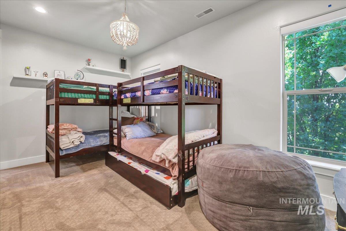 Carpeted bedroom with a chandelier and baseboards