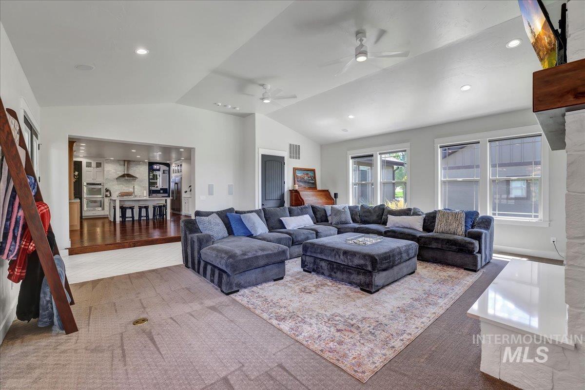 Living room featuring lofted ceiling, ceiling fan, recessed lighting, and wood finished floors