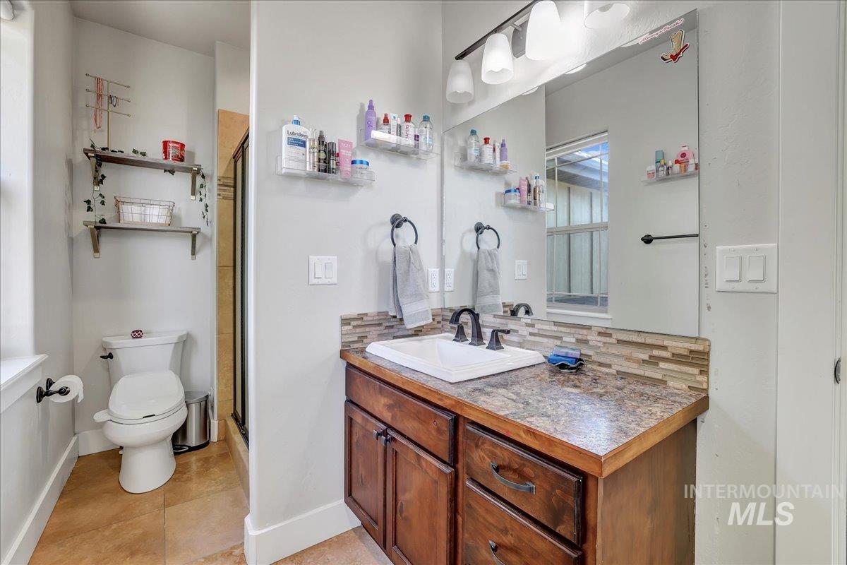 Bathroom with vanity, decorative backsplash, a stall shower, and tile patterned floors