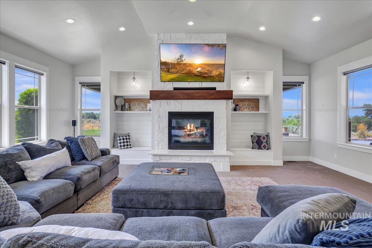 Living room with lofted ceiling, recessed lighting, carpet flooring, and a large fireplace
