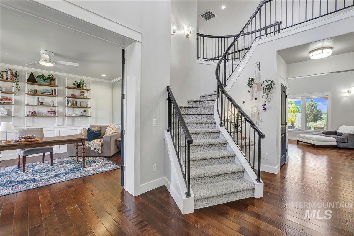 Stairs featuring hardwood / wood-style flooring, a towering ceiling, and ceiling fan