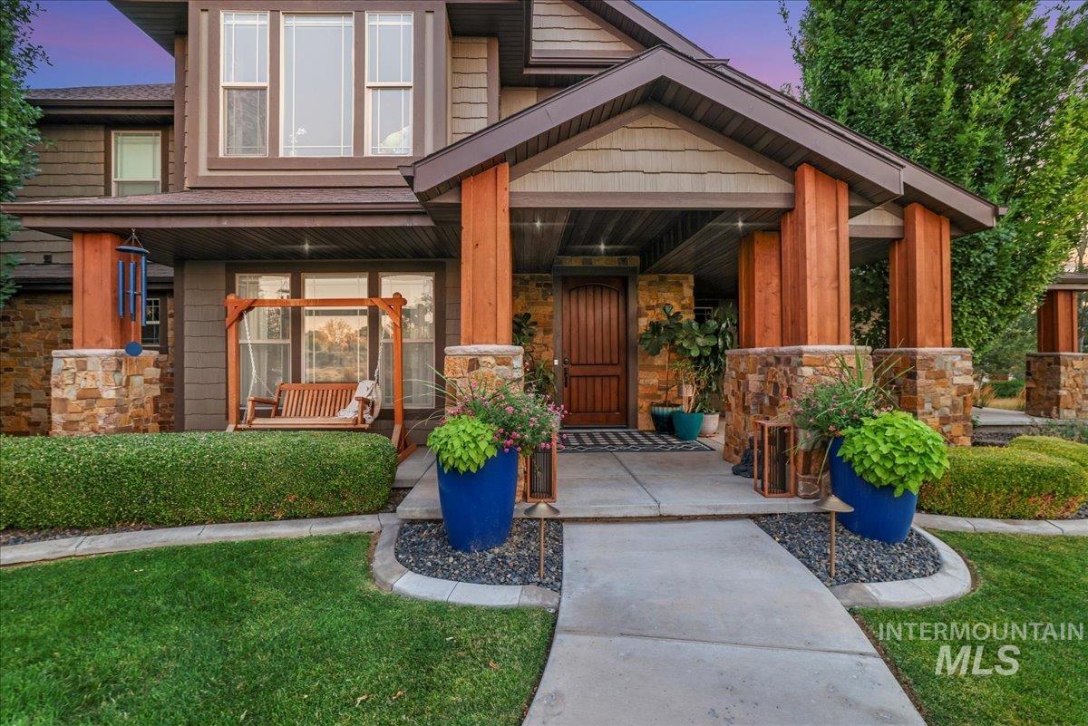 Exterior entry at dusk with stone siding, covered porch, and a yard