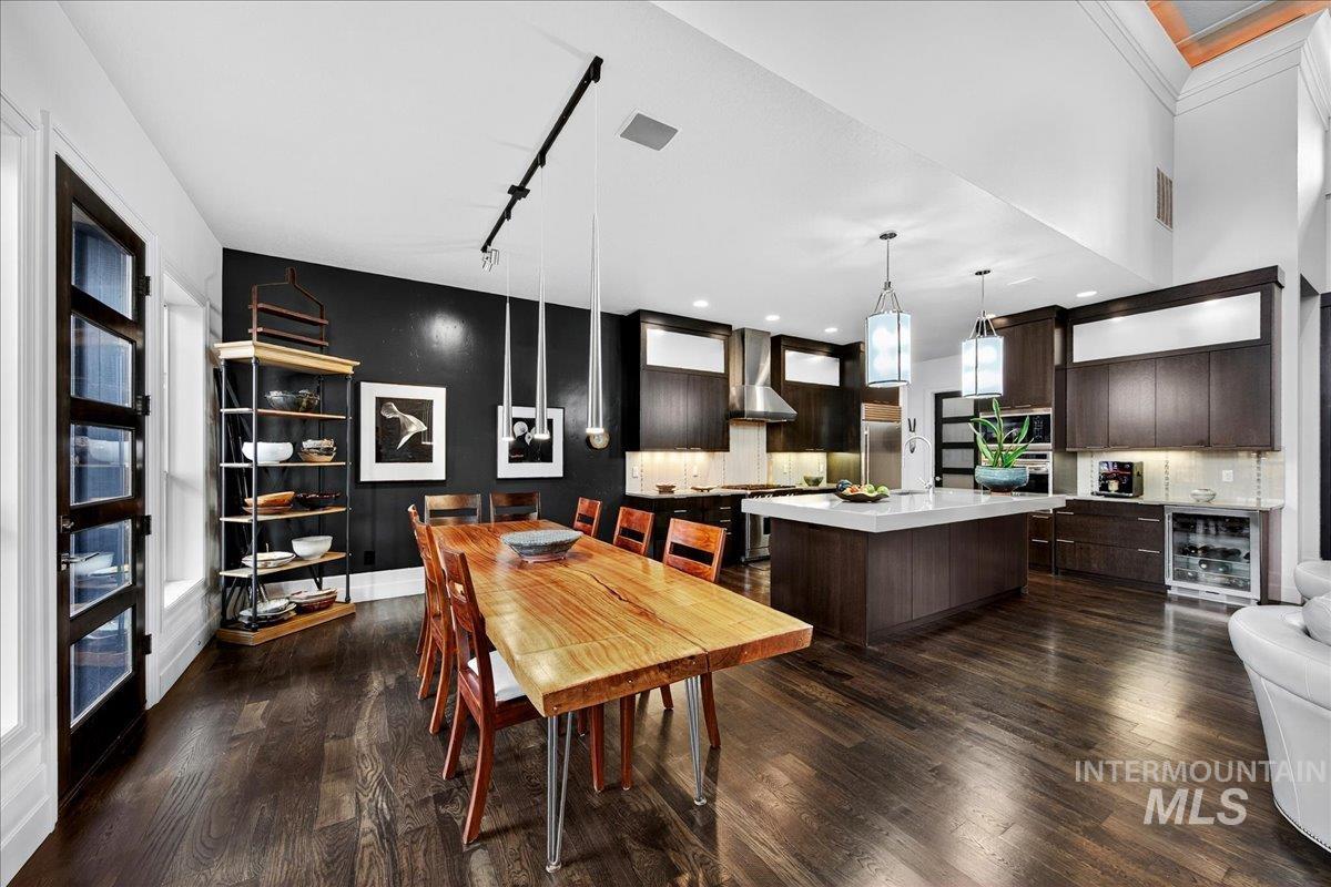 Dining space with dark wood finished floors, beverage cooler, and track lighting