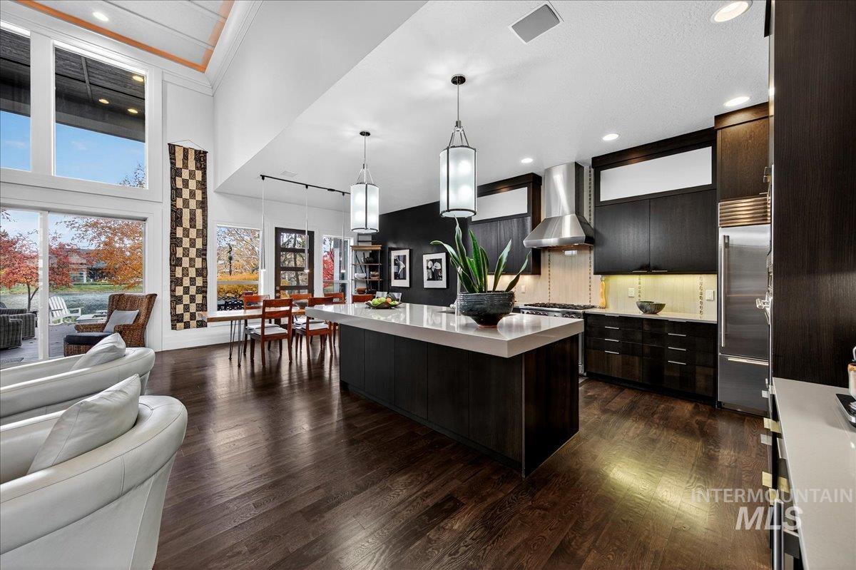 Kitchen with modern cabinets, dark wood-type flooring, a kitchen island, pendant lighting, and a high ceiling