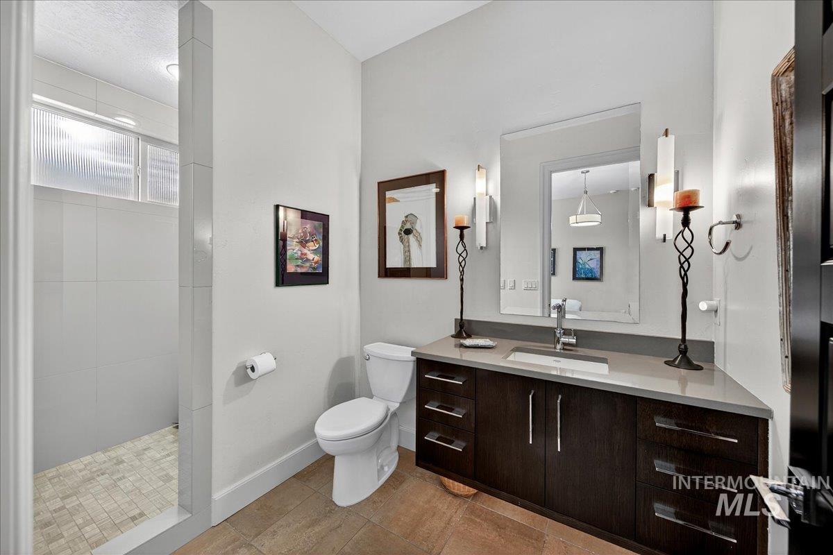 Bathroom with vanity, tiled shower, and light tile patterned floors